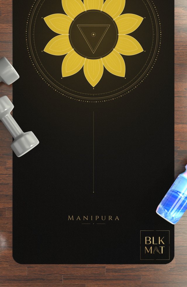 BLKMAT Solar Plexus Chakra yoga mat, flat lay on a wood floor
