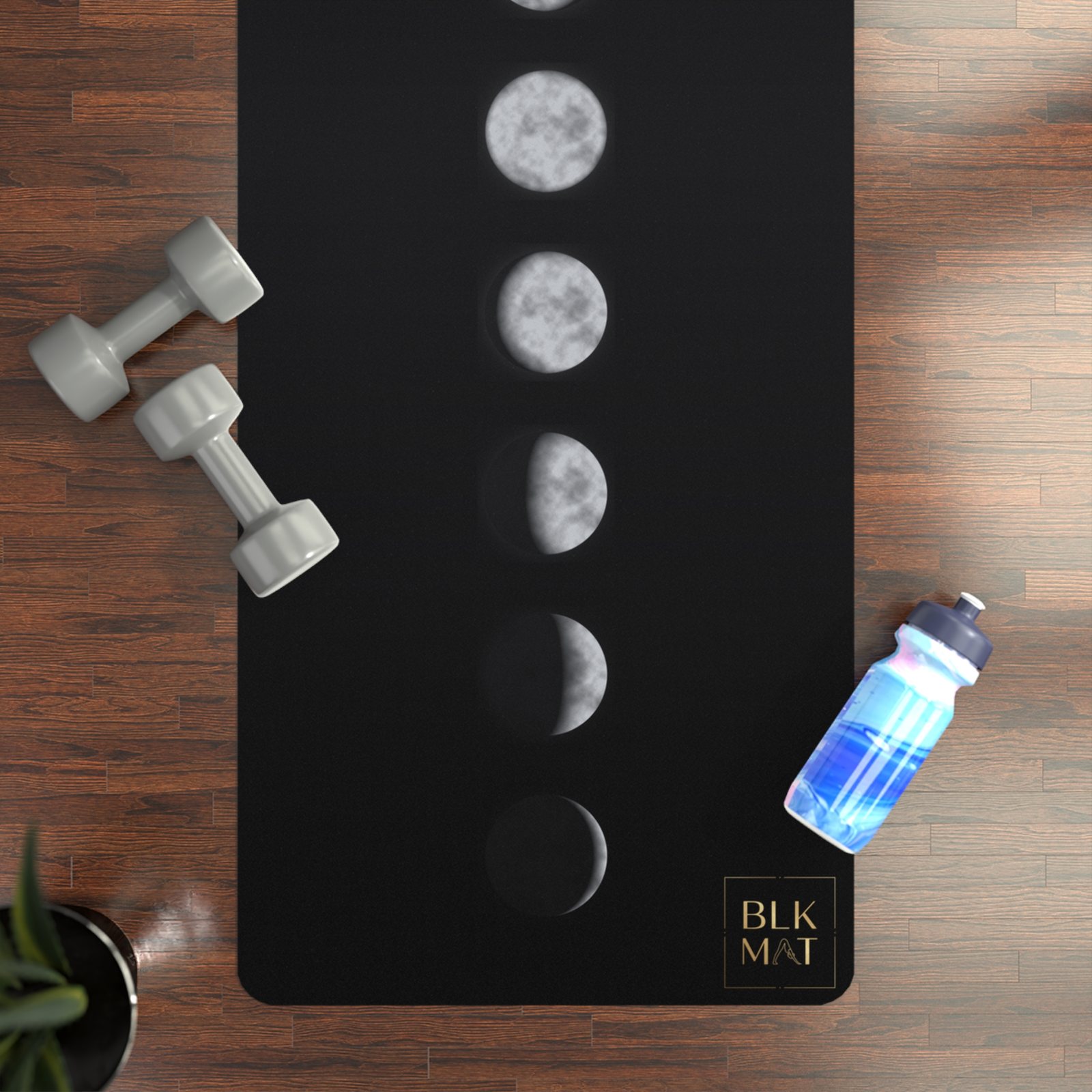 BLKMAT Midnight Moon Phases yoga mat, flat lay on a wood floor