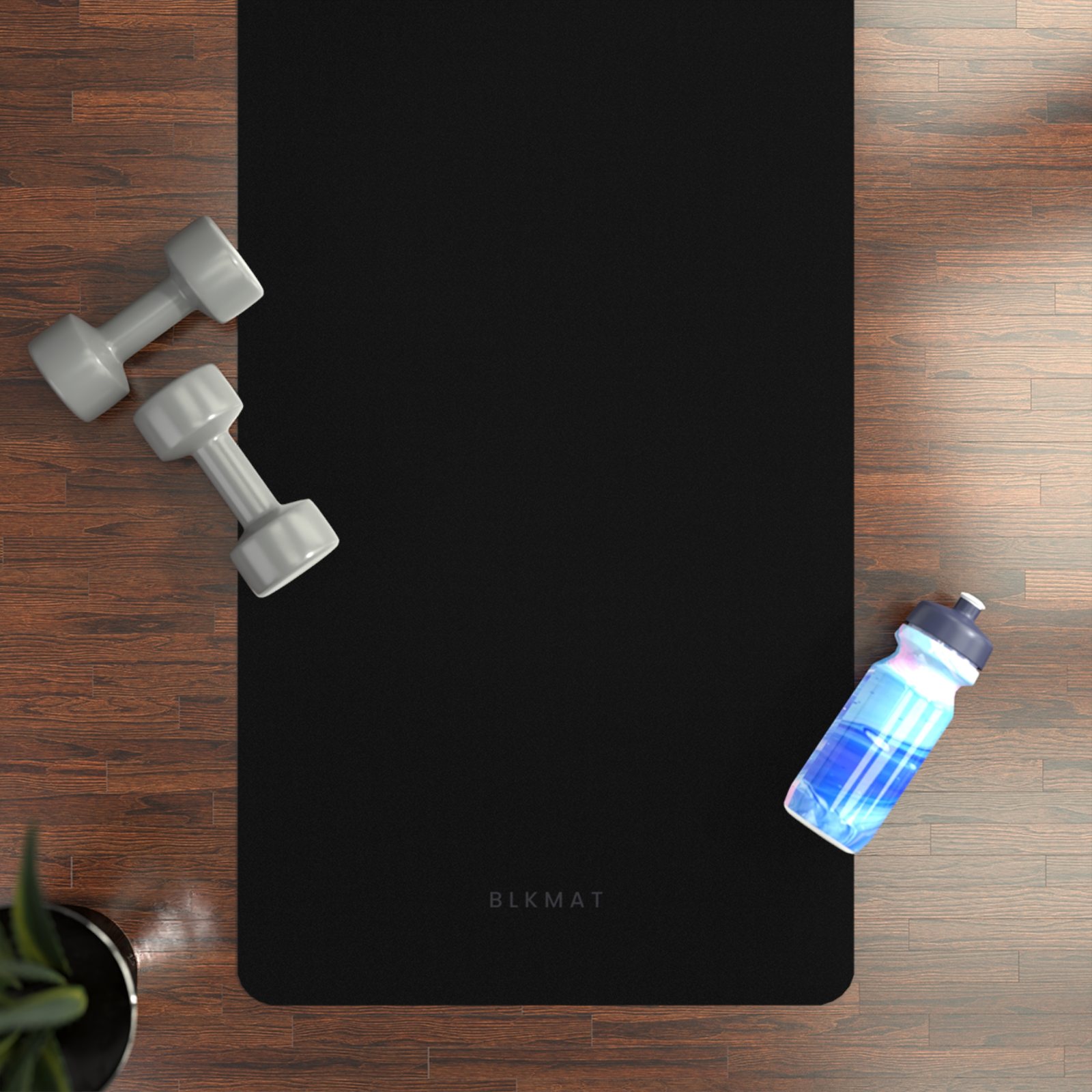 BLKMAT Plain Black yoga mat, flat lay on a wood floor